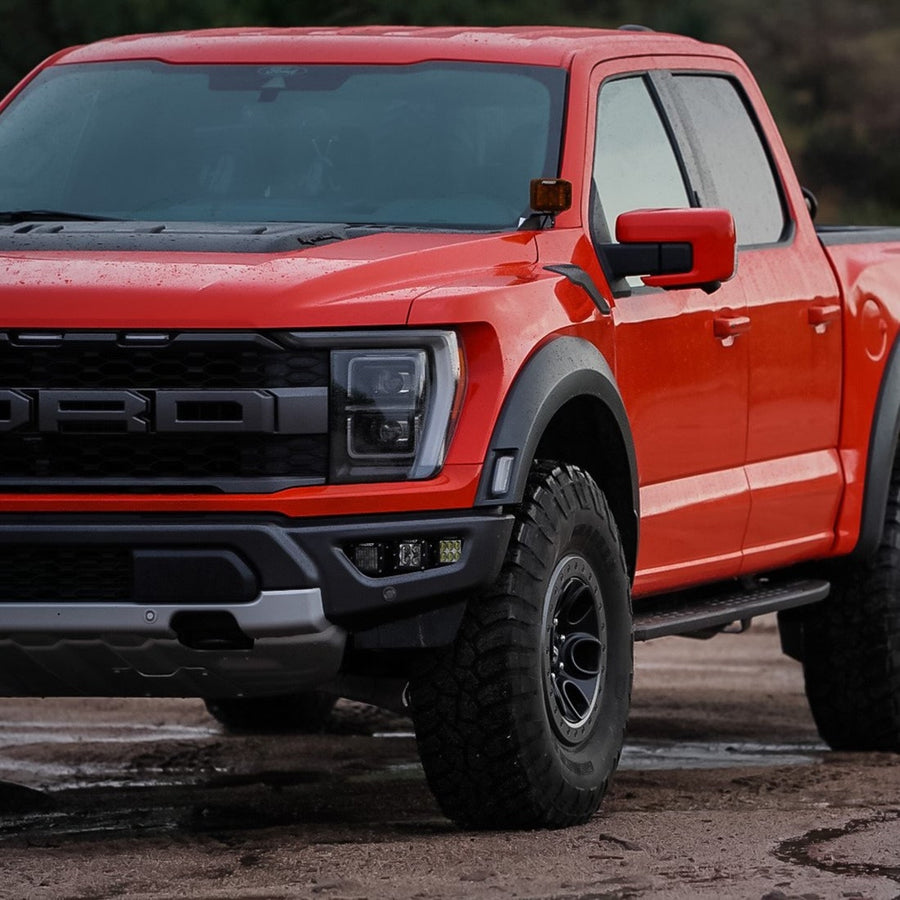 Vehicle-Specific Light Kits by Rigid: Red Ford F-150 Raptor with FORD grille lettering and three square pods in the lower bumper opening.