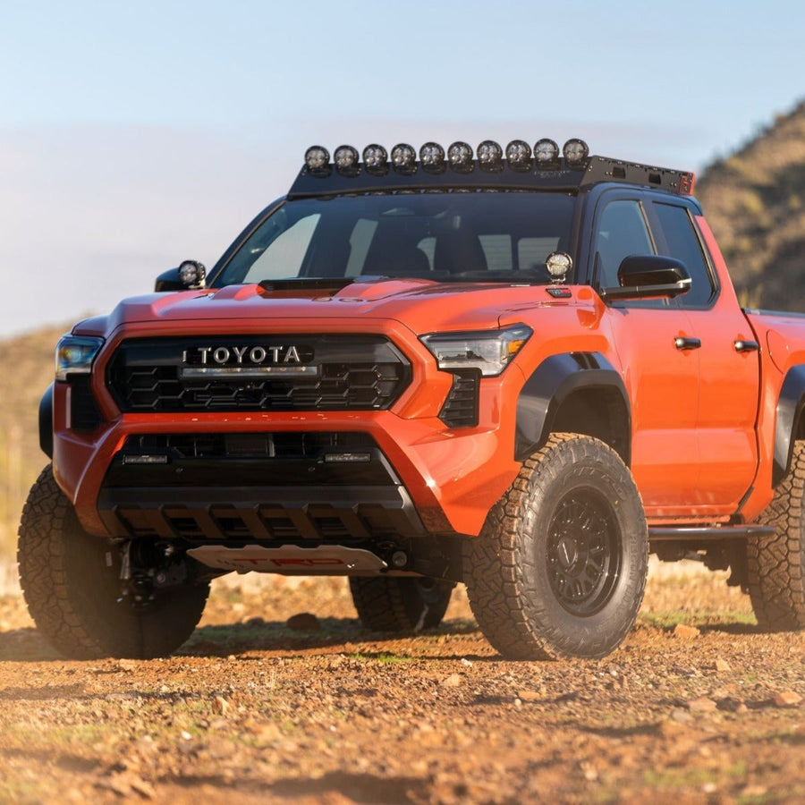 Vehicle-Specific Mounts & Brackets by Rigid: An orange Toyota Tacoma with TOYOTA grille lettering, round lights on both A-pillars and a row of roof rack lights.