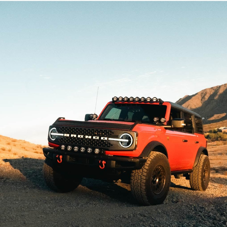 360-Series Round Lights by Rigid: A red Ford Bronco parked on a desert trail with a six-pod light bar mounted across its front bumper.