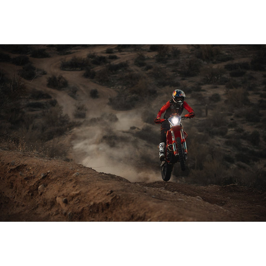 Adapt Adaptive Light Bars by Rigid: A dirt bike rider climbing a dusty hillside trail with the bike headlight on.