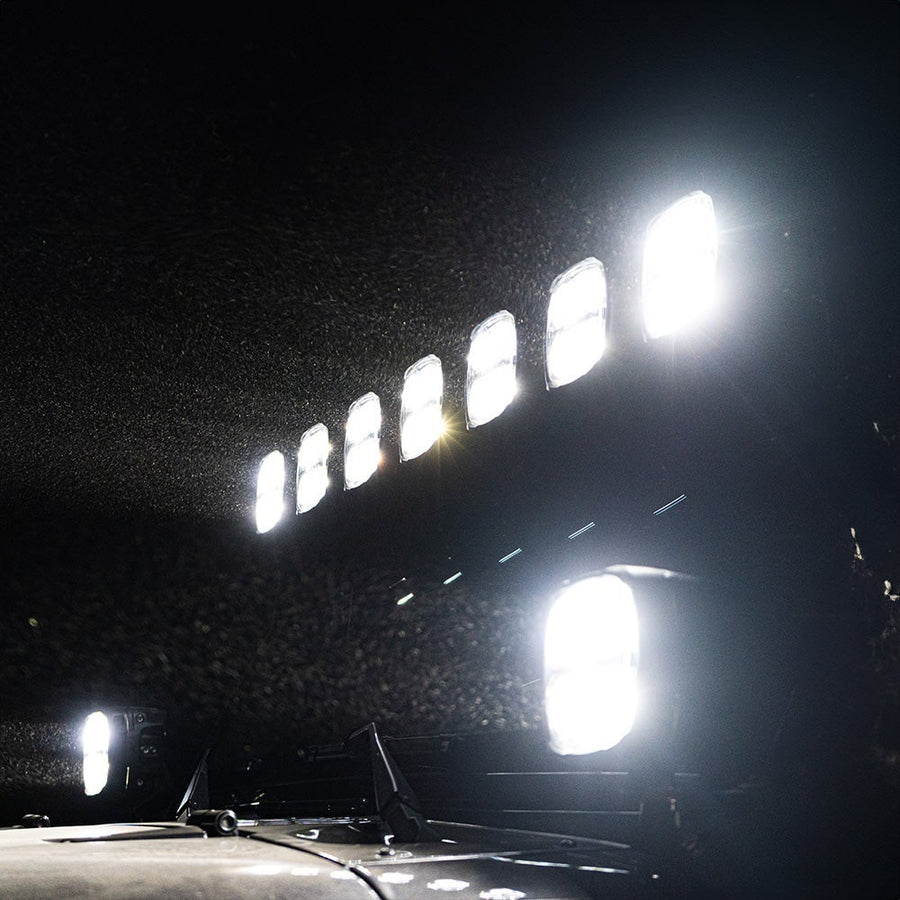 Phoenix Lights by Rigid: Seven roof-mounted pods and two lower pods blazing white over a vehicle at night in drizzle.