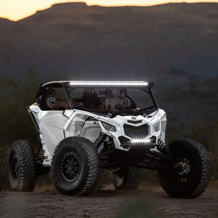 Radiance+ Backlit Lights by Rigid: White side-by-side UTV at dusk with its roof light bar and small bumper light bar shining white.
