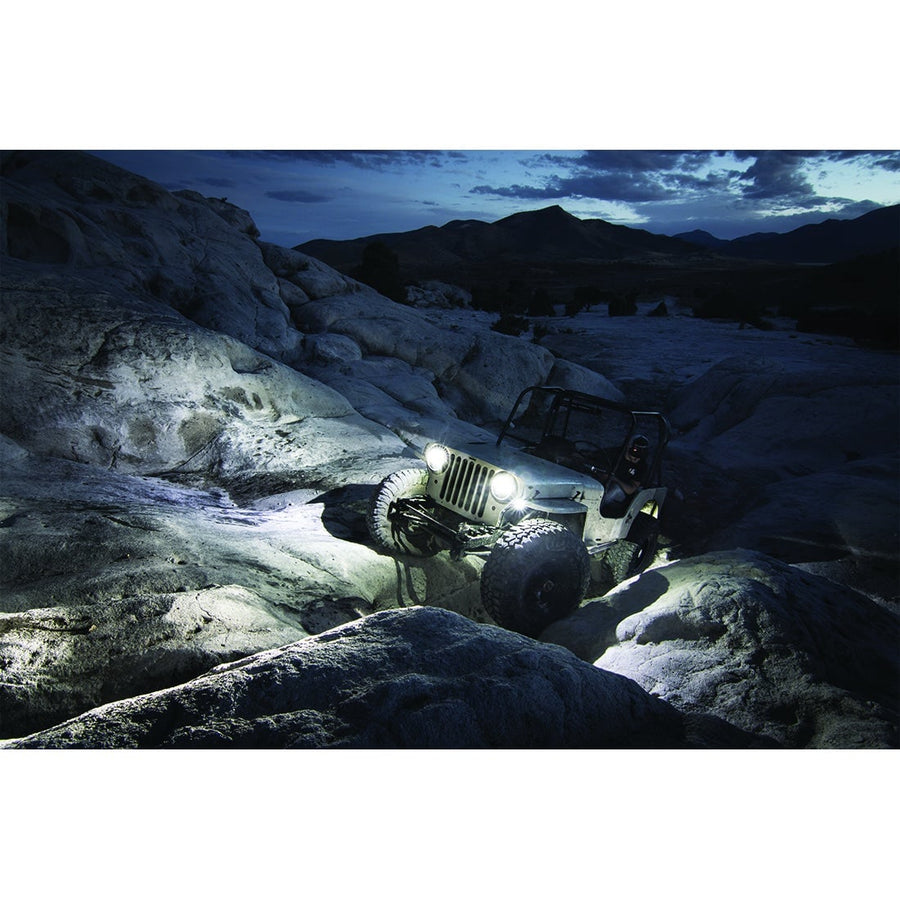 A-Series Rock & Utility Lights by Rigid: A Jeep crawls over pale rock slabs at night with white lights glowing under its body.