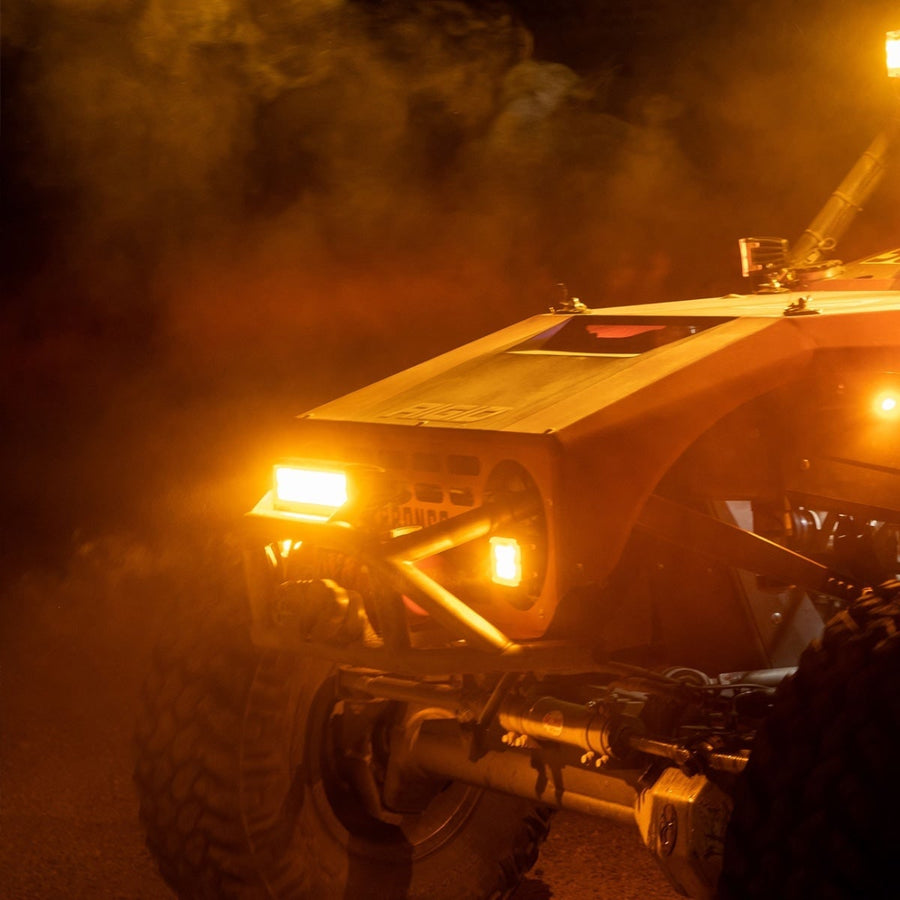 E-Series PRO Light Bars by Rigid: An off-road buggy glows in amber light through night-time dust.