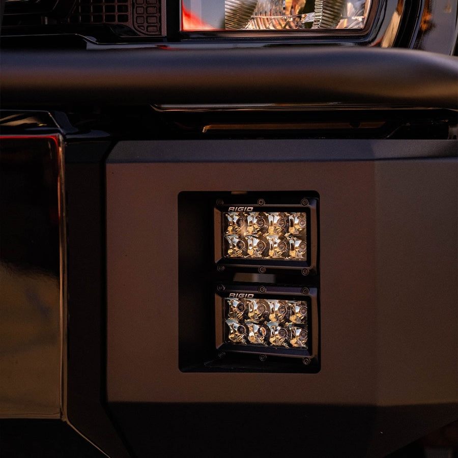 E-Series PRO Light Bars by Rigid: Two 4 inch E-Series lights stacked in a black bumper fog pocket below a truck headlight at sunset.