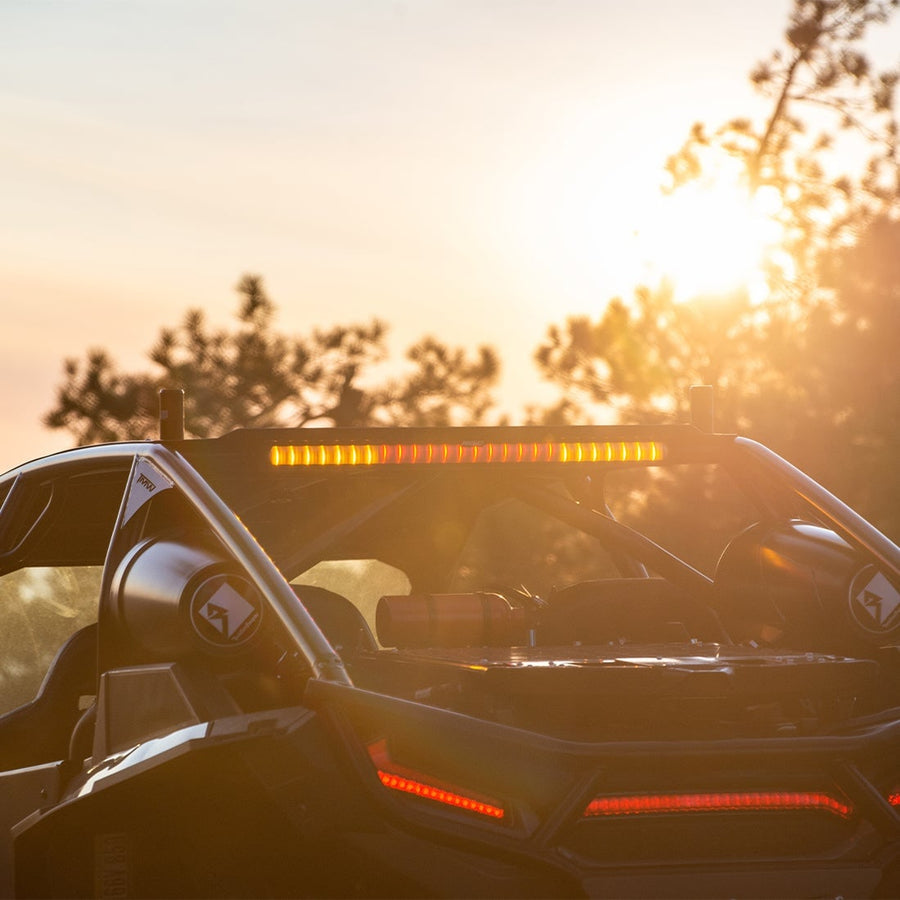 Light Mounts & Hardware by Rigid: A UTV at sunset shows an amber Chase light bar on its roof and red tail lights.