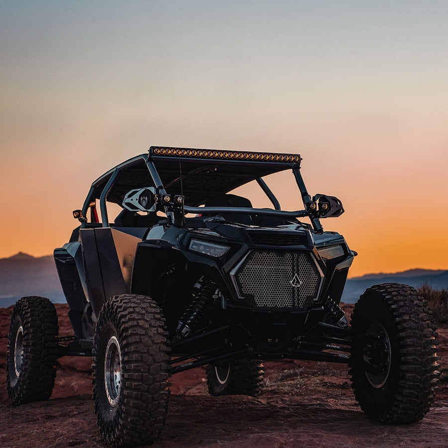 Revolve Lights by Rigid: A black Polaris RZR side-by-side on red rock at dusk with a roof-mounted LED light bar.