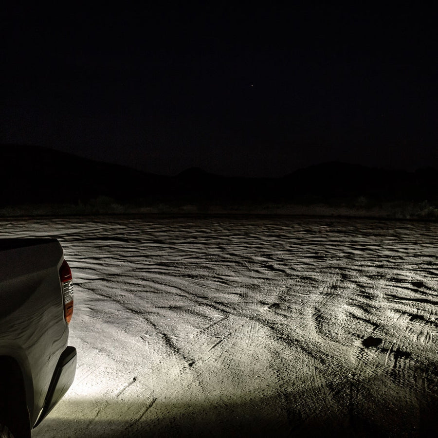 SR-L Lights by Rigid: A white work light floods sandy ground beside a truck at night.