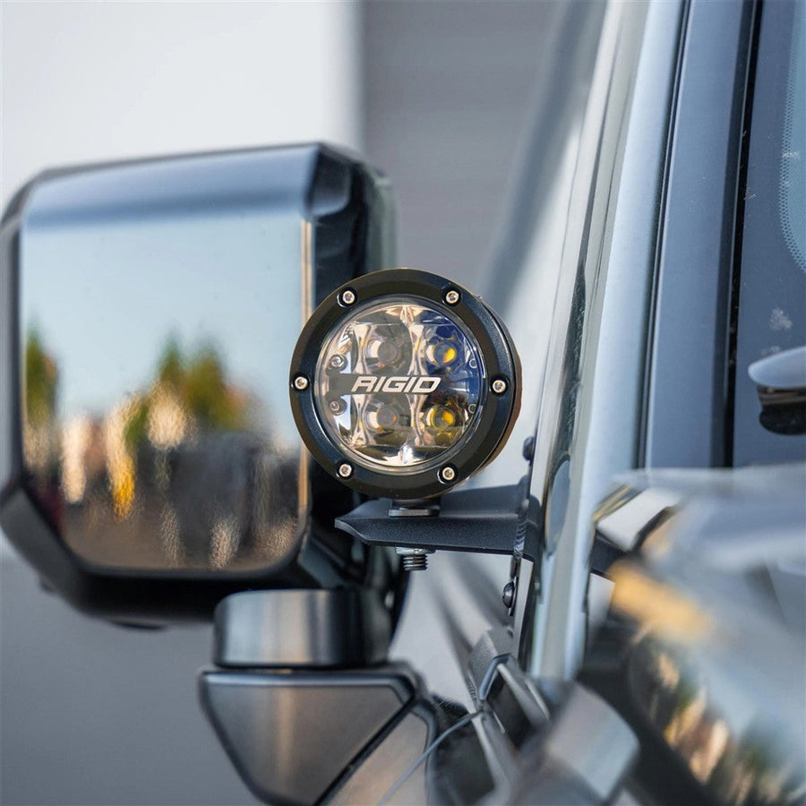 Vehicle-Specific Light Kits by Rigid: Round 360-Series spot light on an A-pillar bracket next to the side mirror of a gray vehicle