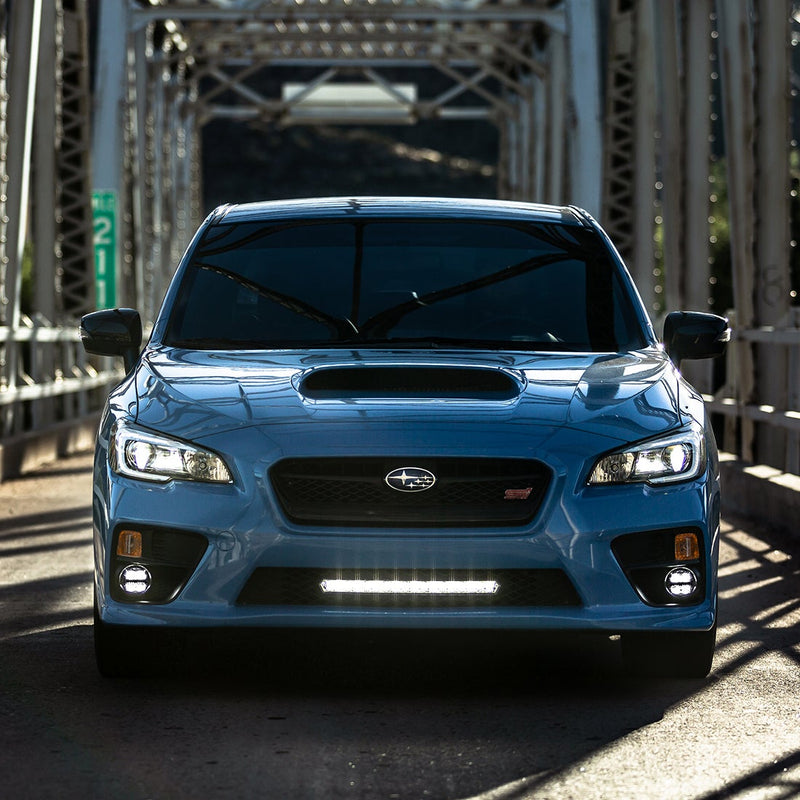 Rigid SR-L Series 20" LED bar lit white in the lower grille of a blue sedan on a steel bridge