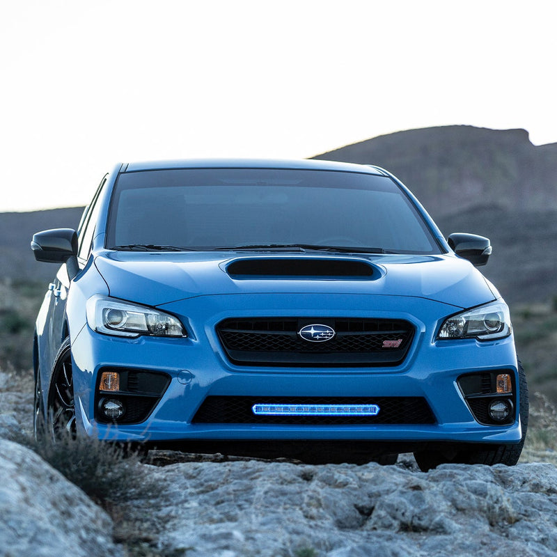 Rigid SR-L Series 20" LED bar mounted in the lower grille of a blue sedan parked on rocks
