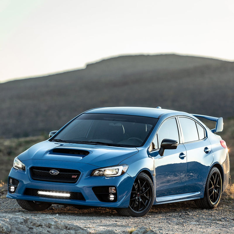 Rigid SR-L Series 20" LED bar mounted low in the front bumper of a blue sedan on a hillside