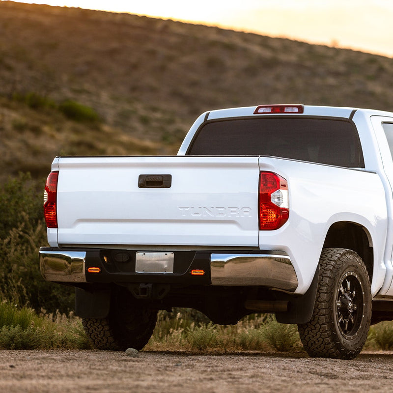 Rigid SR-L Series Spreader Flush Mounts with Red Halo Pair installed on a Toyota Tundra: A white Toyota Tundra seen from the rear with two small lights glowing in the rear bumper