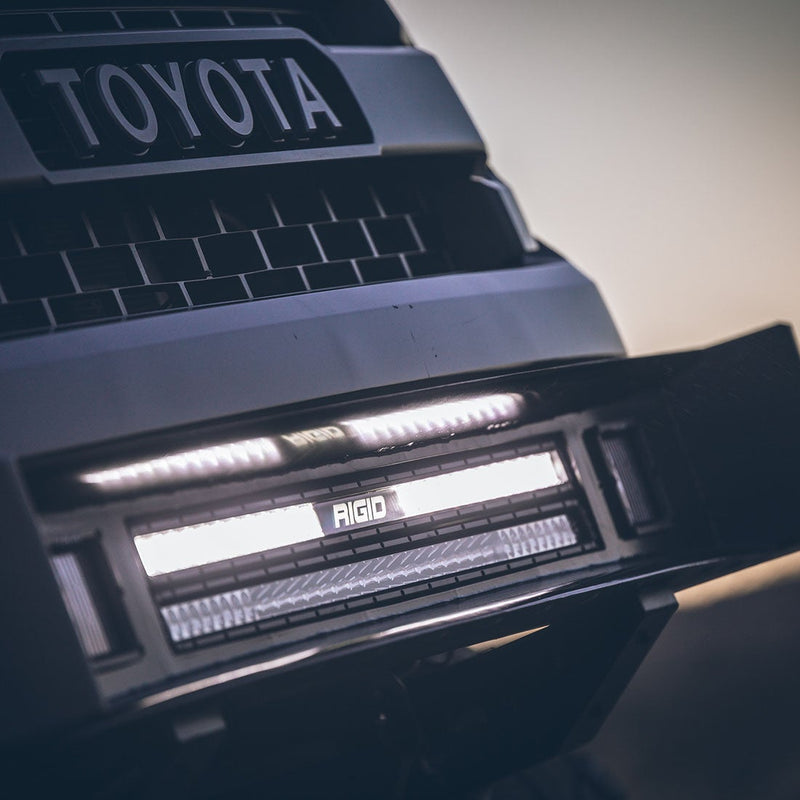 Rigid SR-Series 30" Dual Function SAE with White Backlight installed on a Toyota Tundra: close view of a lit Rigid light bar set in the front bumper below a Toyota Tundra grille