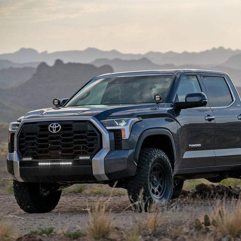 Rigid 360-Series 4" Drive A-Pillar Light Kit: gray Toyota Tundra with TUNDRA door badge, round A-pillar pods and lit lower bumper lights in the desert