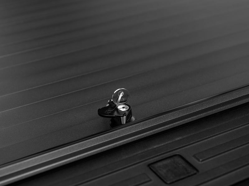 Roll-N-Lock A-Series keyed lock cylinder and key on the aluminum slat surface