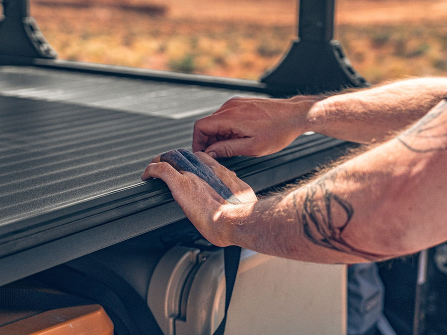 Hand sliding a Roll-N-Lock A-Series XT cover open, desert background
