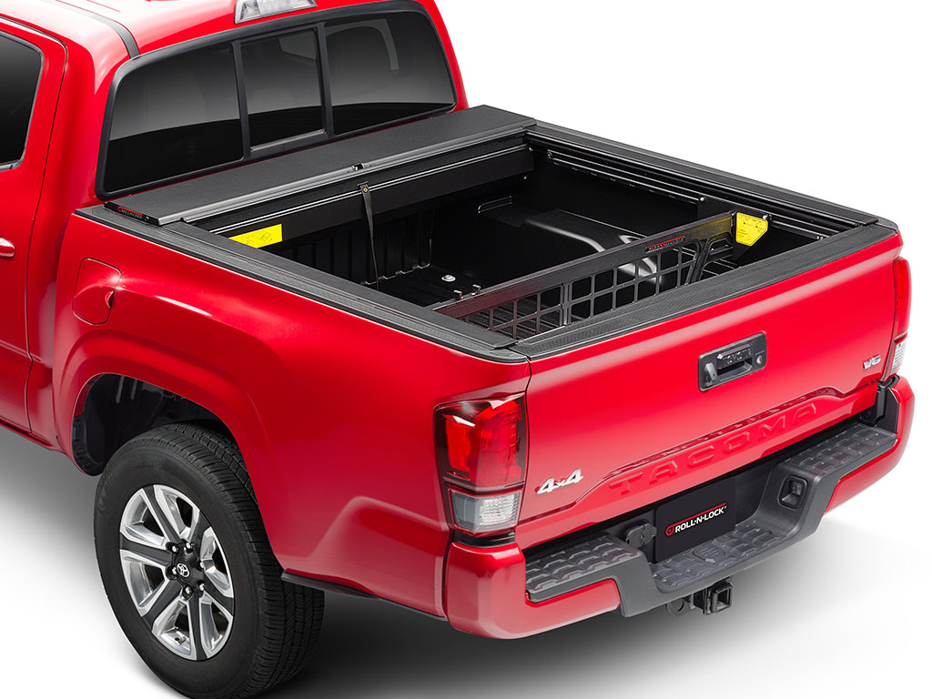 Roll-N-Lock Cargo Manager raised in the bed of a 2016-2023 Toyota Tacoma, rear three-quarter view with the tailgate up