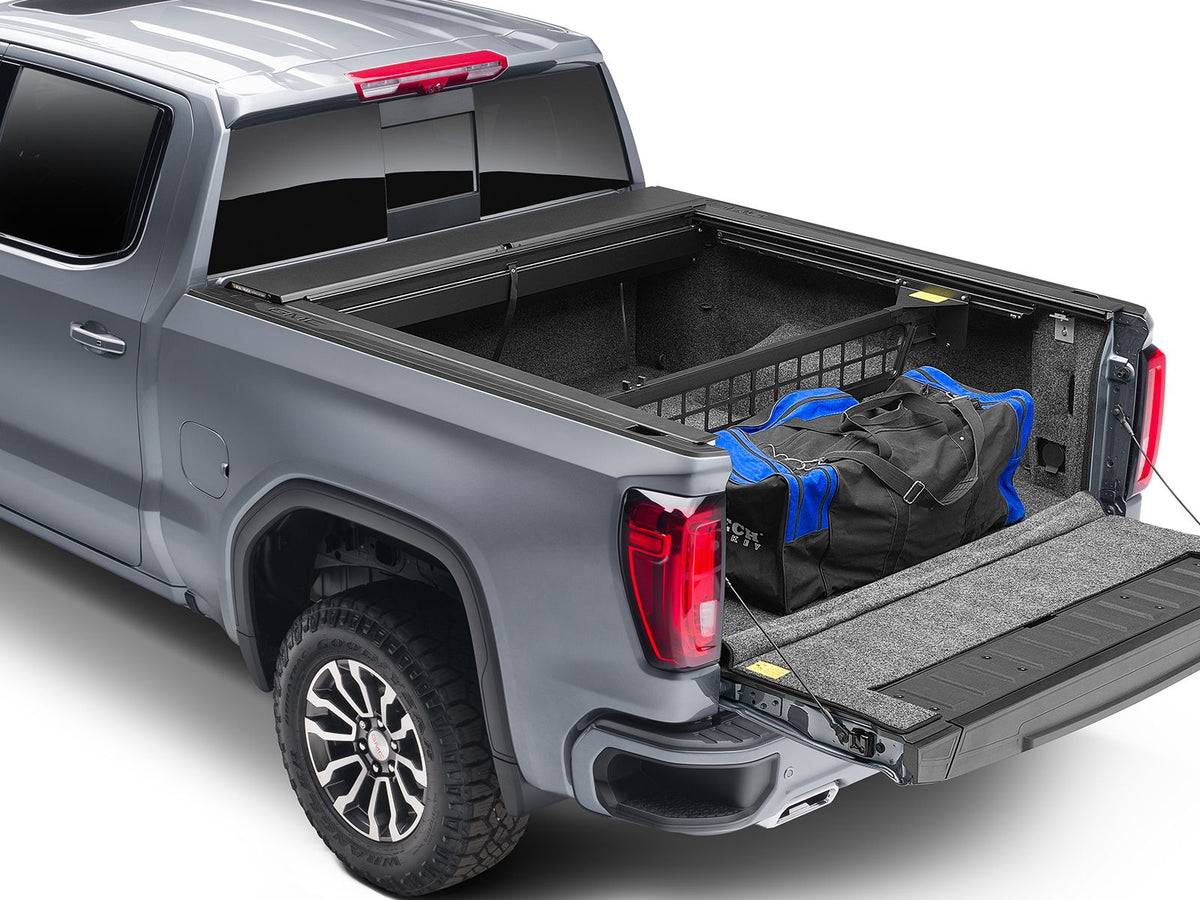 Roll-N-Lock Cargo Manager raised across an open pickup bed holding a duffel against the bulkhead, tailgate down