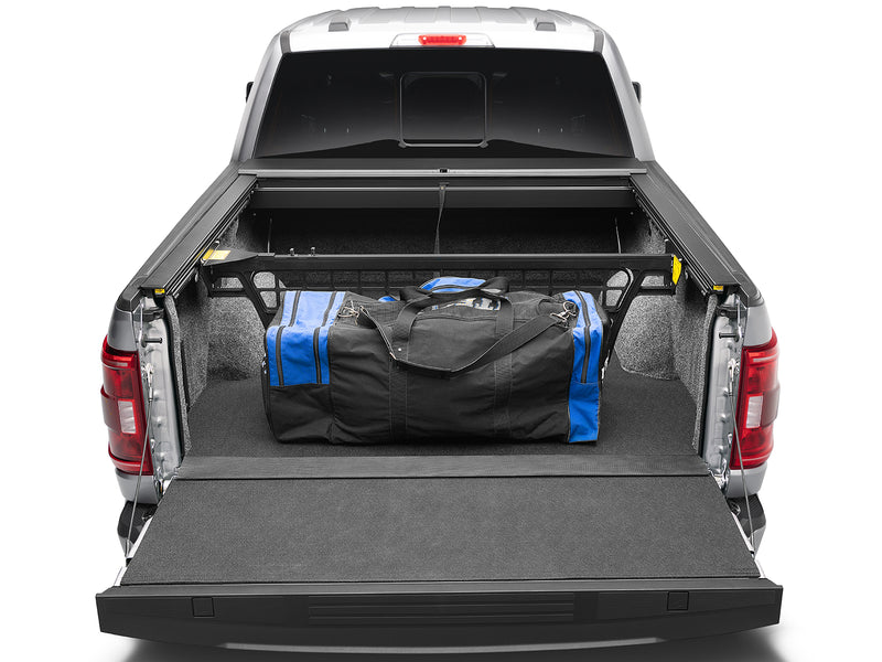 Roll-N-Lock Cargo Manager stowed against the bulkhead retaining a duffel, seen from the open tailgate