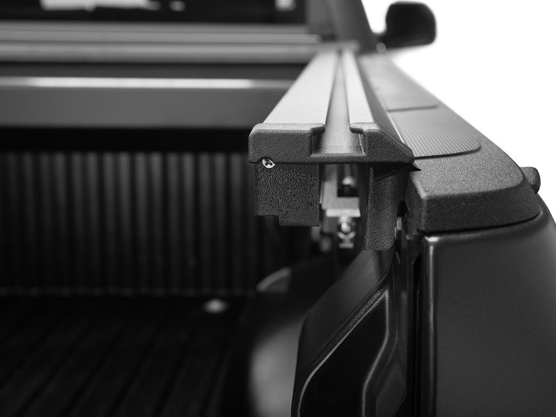 Roll-N-Lock E-Series XT MaxTrak rail end cap and its catch, bed ribs behind