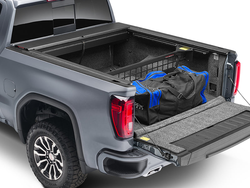 Roll-N-Lock Cargo Manager bed divider holding a duffel at the bulkhead, rear three-quarter (tonneau cover sold separately)