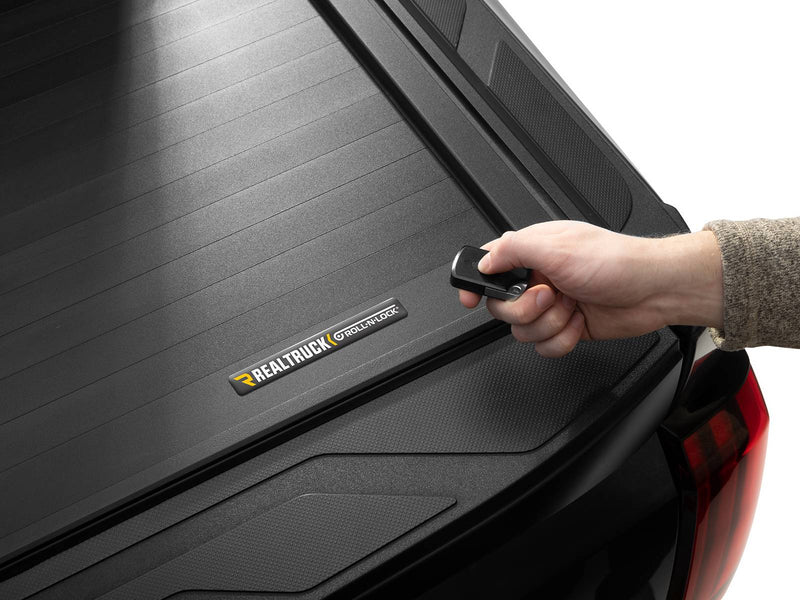 Roll-N-Lock E-Series XT hand pressing the key fob over the closed cover, Roll-N-Lock badge in view