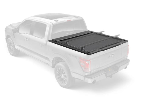 Roll-N-Lock M-Series XT closed over a pickup bed with T-slot rails, ghosted truck so the cover stands out; crossbars sold separately