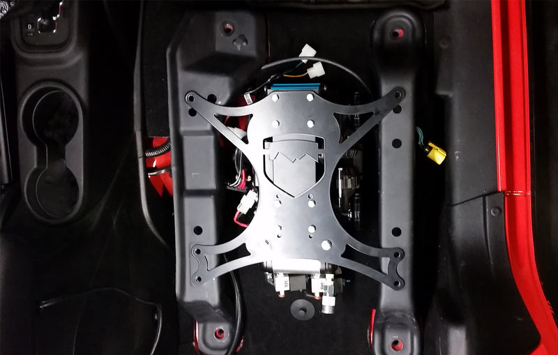 TeraFlex air compressor mount plate installed under the front seat of a red Jeep