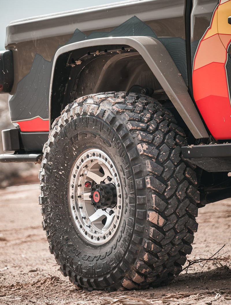 Close-up of the TeraFlex HD Axle: muddy rear tire on a beadlock wheel under a Gladiator bed fender flare