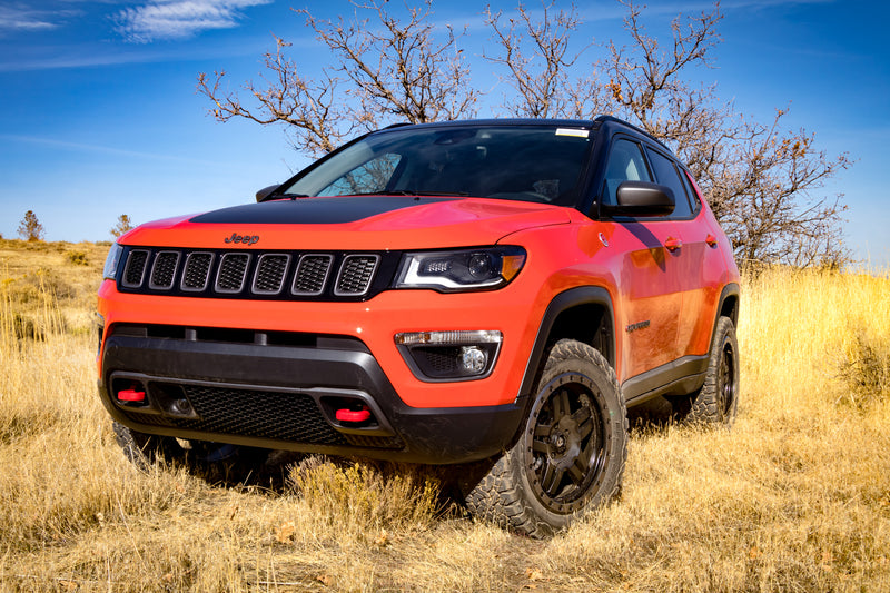 Orange Jeep Compass with the TeraFlex 1.5" Performance Spacer Lift Kit installed, in a grassy field