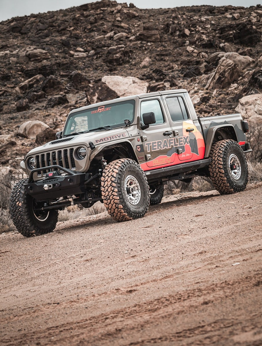 Tan lifted Jeep Gladiator Mojave with TeraFlex livery on a rocky desert trail