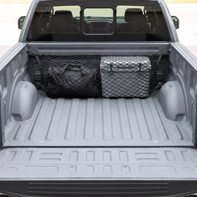 Black cargo net stretched across the front of a grey pickup truck bed, holding a black duffel bag and a plain grey cooler against the bulkhead, with a black plastic snap hook clipped to a small wall mount at each corner