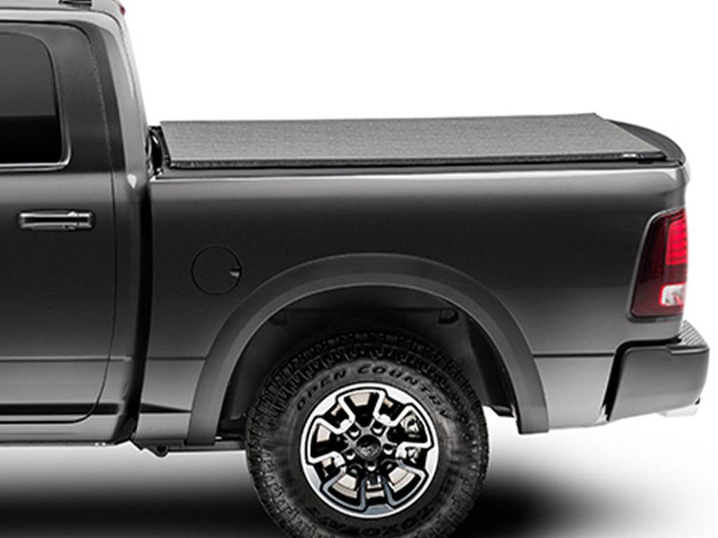 Black soft folding tonneau cover closed flat over a pickup bed, side profile on a white background