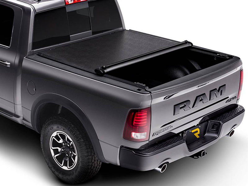 Soft tonneau cover rolled partway forward from the tailgate, roll resting mid-bed with the rear half of the bed open