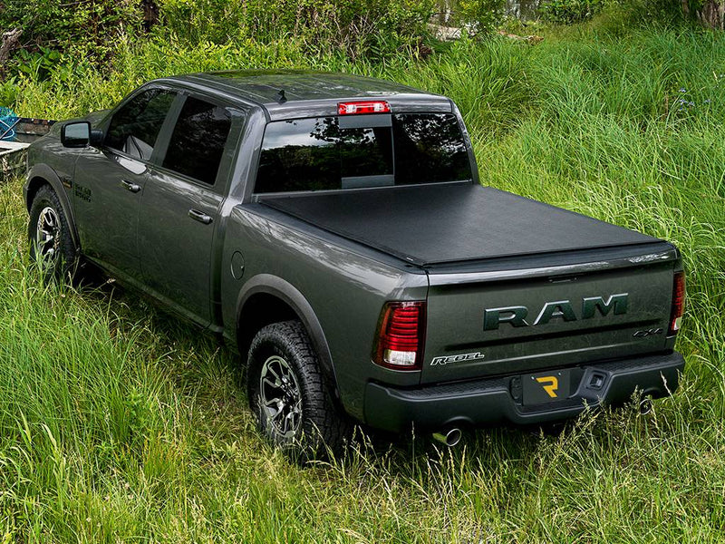 Gray pickup in a grassy field with the black soft tonneau cover closed