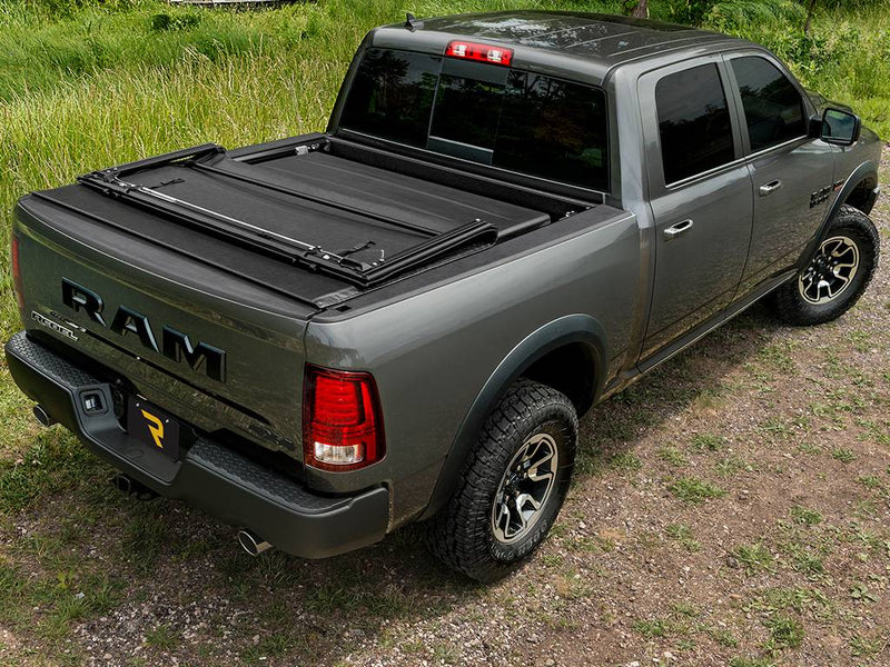 Gray pickup outdoors with the cover rolled to the front and the front section folded