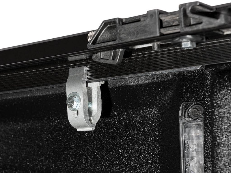 Close-up of a side rail clamp bolted under the bed rail; the LED bed light at right is not included