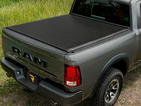 TruXedo Deuce soft folding tonneau cover closed over the bed of a pickup truck, straight rear view, standing on a grass verge, photographed on location