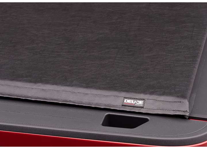 Close-up of the DEUCE name plate at one end of the cover's rear edge, seen from above on a TruXedo Deuce soft folding tonneau cover