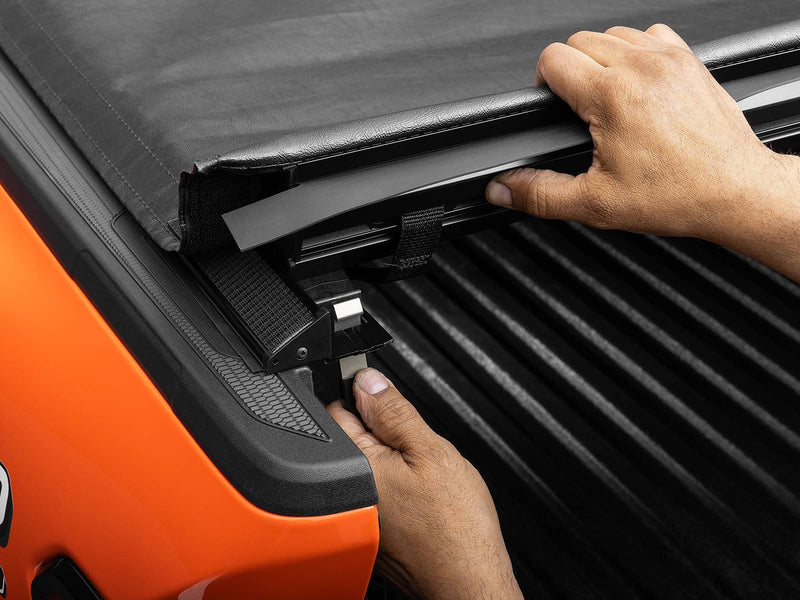 Hands releasing the Lo Pro rear latch with one finger while lifting the cover edge