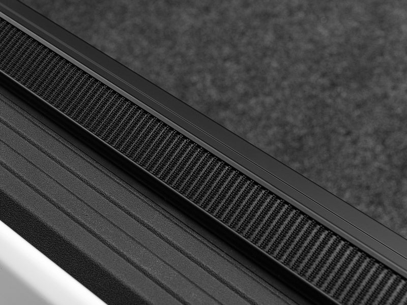 Close-up of the hook-and-loop strip running the length of the side rail, seen at a shallow angle on a TruXedo Lo Pro soft roll-up tonneau cover