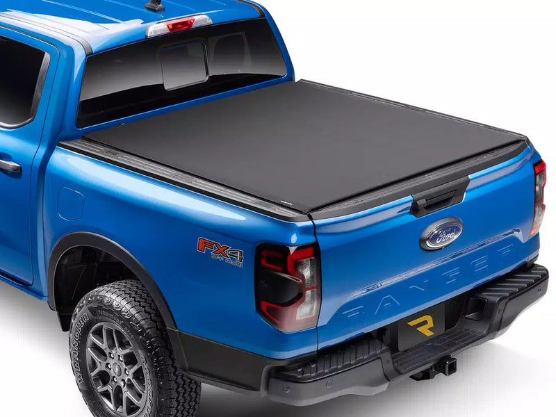 Soft roll-up tonneau cover closed on a blue midsize pickup, rear three-quarter view