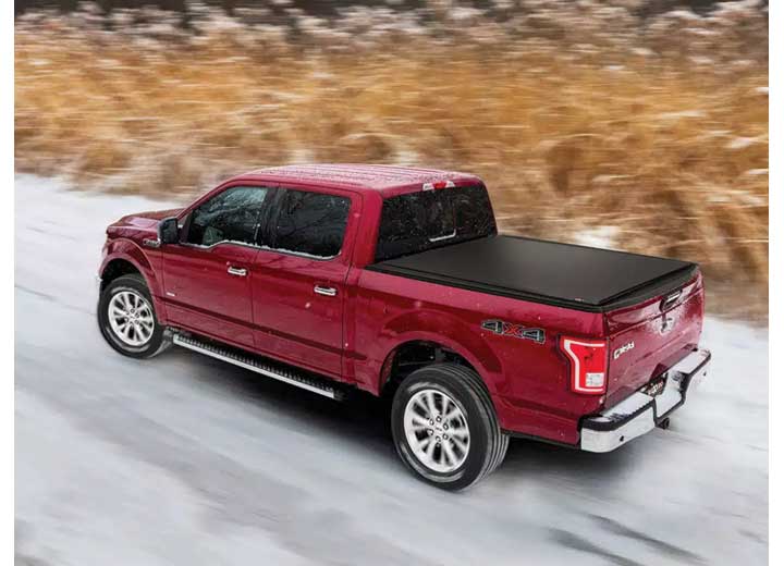 TruXedo Pro X15 soft roll-up tonneau cover closed on a 2015-2020 Ford F-150, side profile, on a snow-covered road, motion-blurred, photographed on location