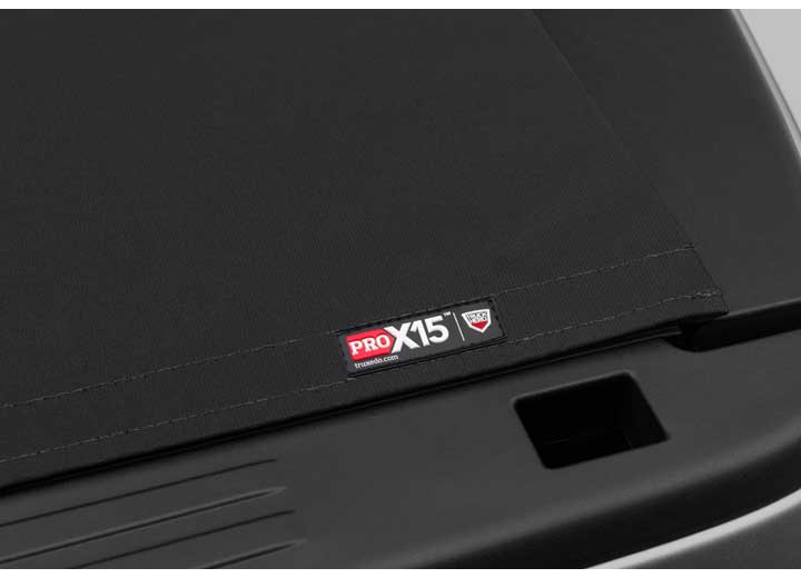 Close-up of the PRO X15 name plate on the flat cover surface, a squared tailgate handle recess below on a TruXedo Pro X15 soft roll-up tonneau cover