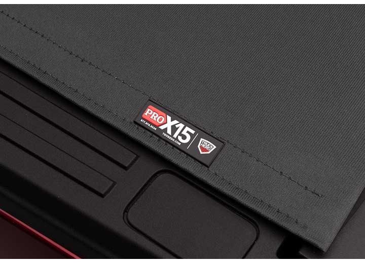 Close-up of the PRO X15 name plate on the cover's rear seam, a long stamped bedside recess below on a TruXedo Pro X15 soft roll-up tonneau cover