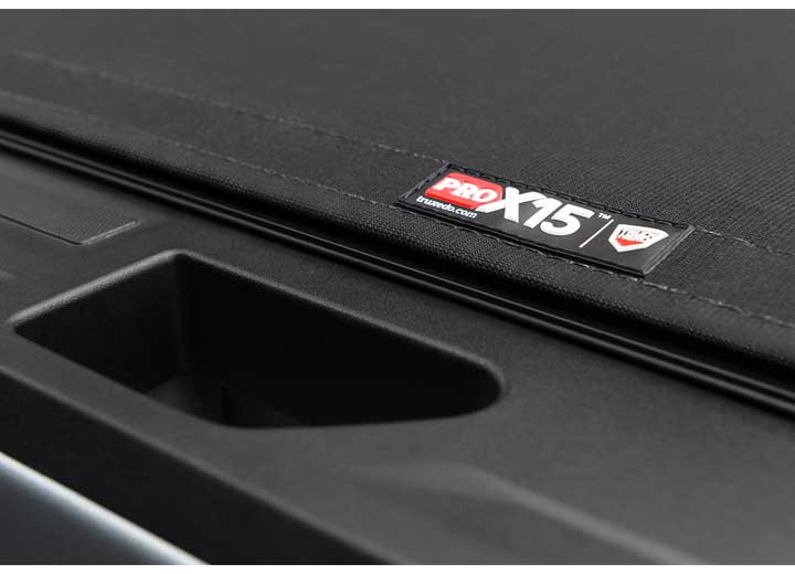 Close-up of the PRO X15 name plate alongside the tailgate handle recess, seen from directly above on a TruXedo Pro X15 soft roll-up tonneau cover