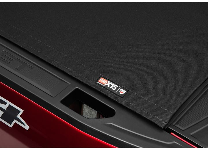 Close-up of the PRO X15 name plate directly above an open tailgate handle recess, a red bedside below on a TruXedo Pro X15 soft roll-up tonneau cover