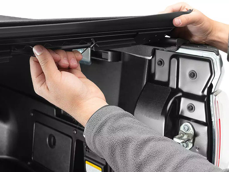 Hands lifting the rear end of the Sentry cover and releasing its latch at the tailgate