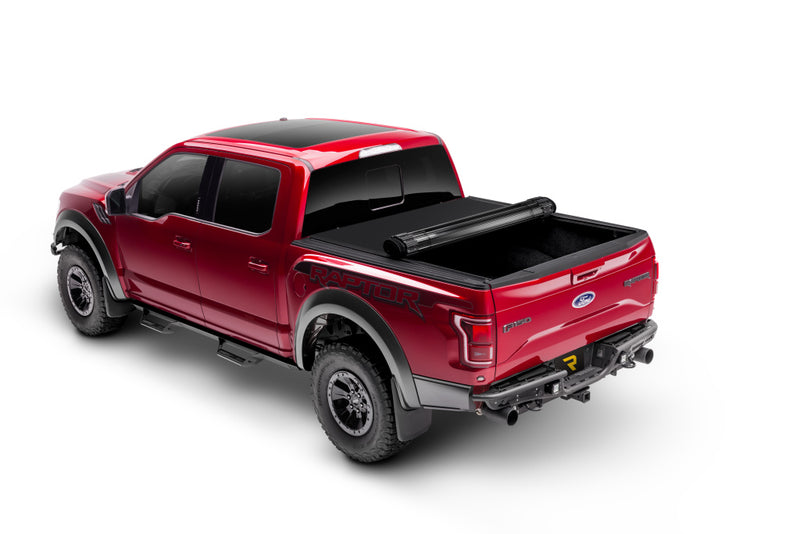 TruXedo Sentry CT hard roll-up tonneau cover rolled partway open over the bed of a pickup truck, distant rear three-quarter view